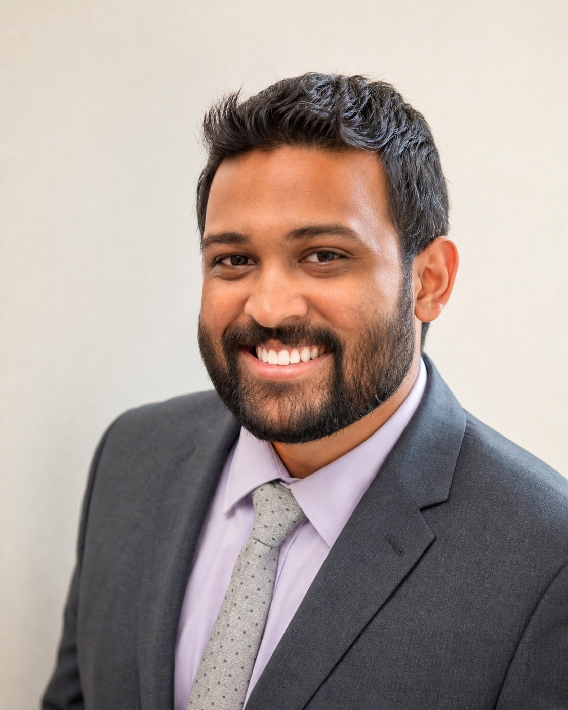 Mihir Amin smiling in a charcoal suit